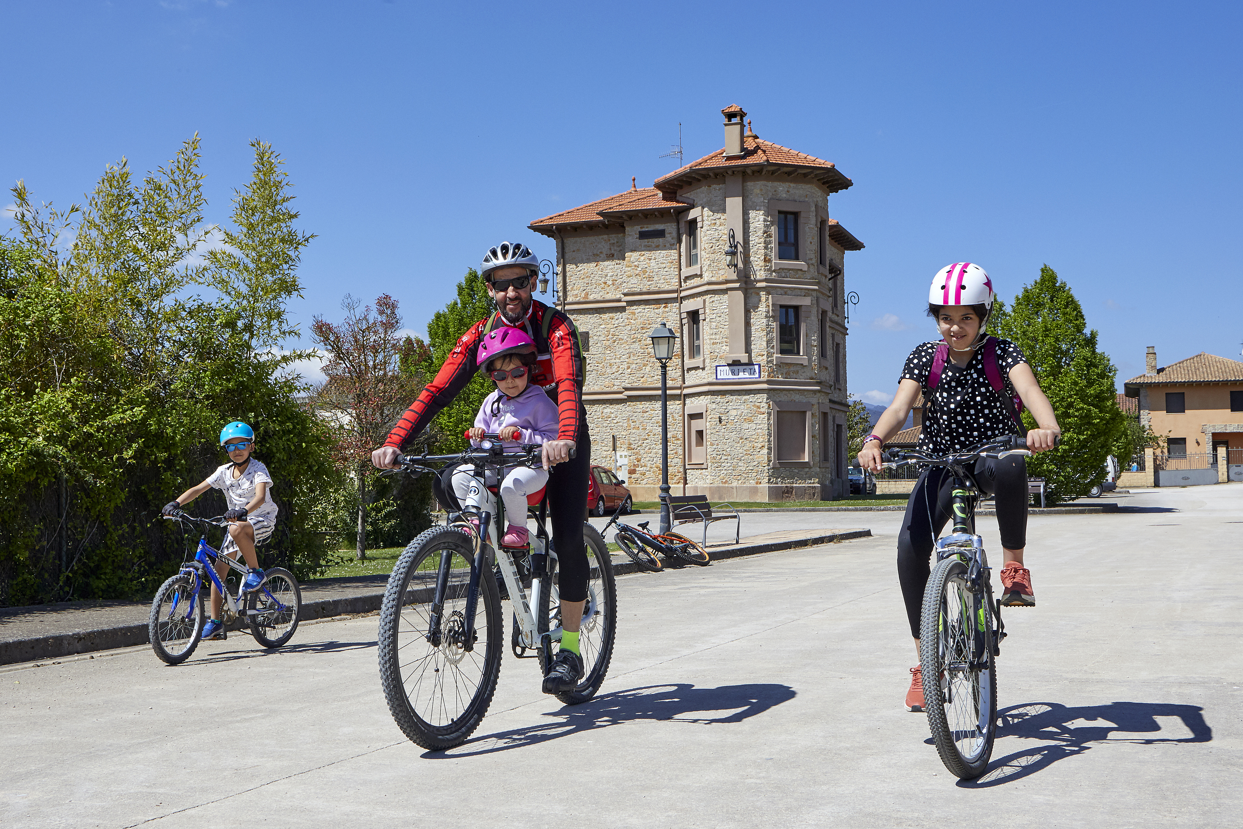 Un adulto y tres niños andando en bici por la vía verde del Vasco-Navarro